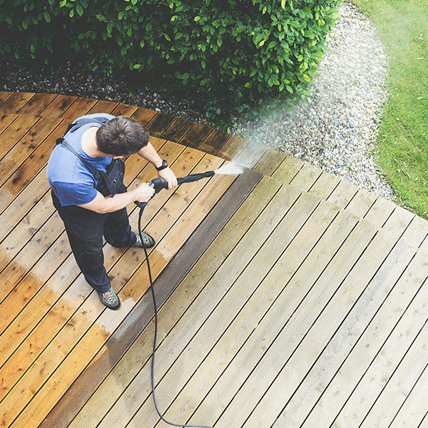 professional in blue shirt cleaning wooden deck