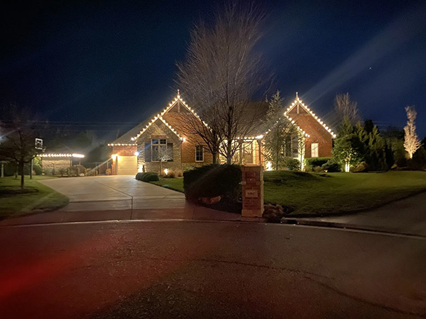 brick home with white holiday lighting