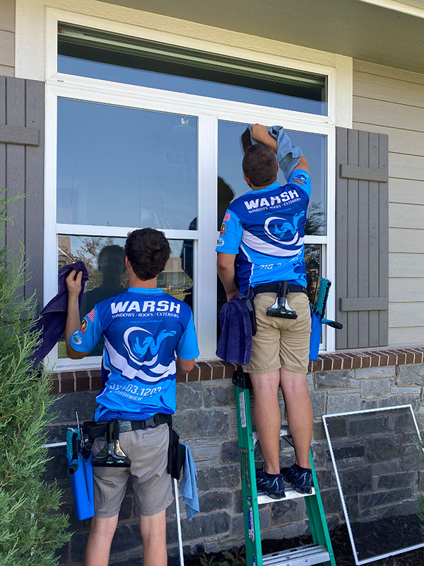Warsh professionals cleaning exterior windows on brown home